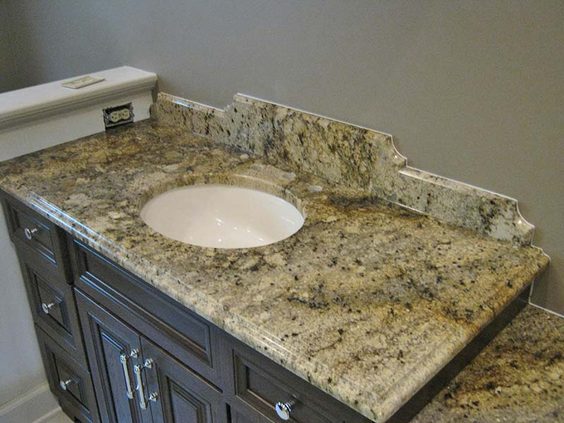 The earthtone shades of Spring Beige Granite really pop over the dark brown cabinets.