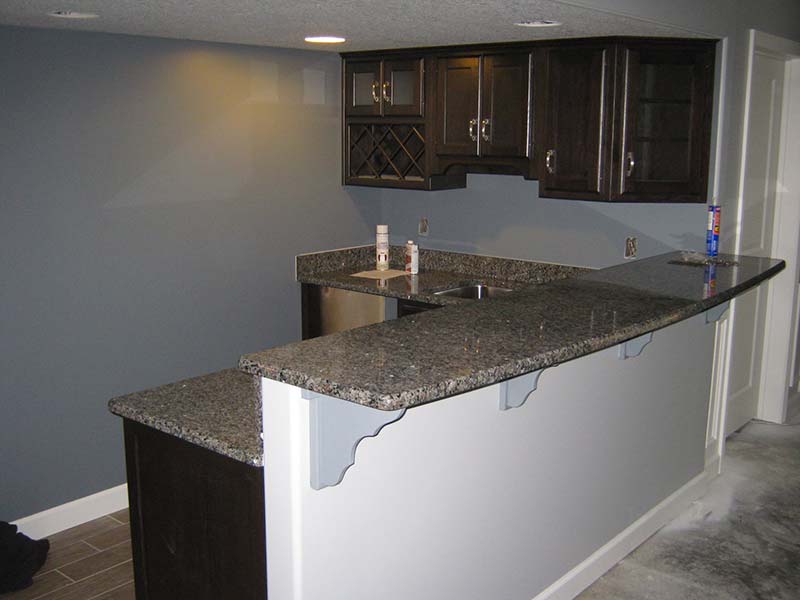 Caledonia Granite counter, wet bar, and sink over brown and white cabinets.