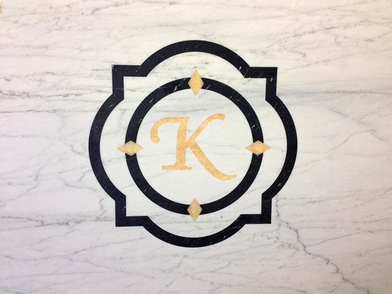 Bianco Carrera Marble with monogram inlay in gold and black.