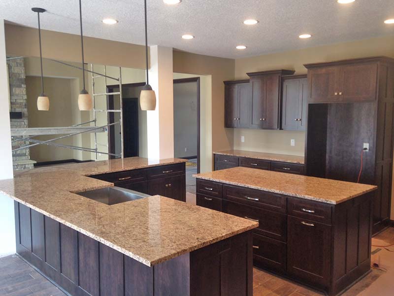Giallo Ornamental Granite kitchen counters and center island show off this large kitchen with dark wood cabinets. 